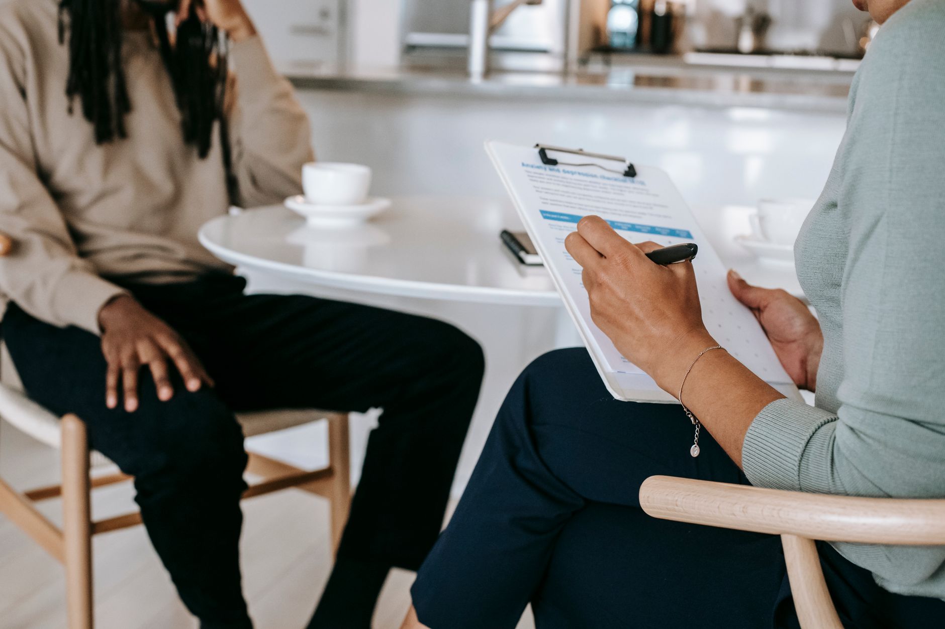 Professionnelle RH prenant des notes sur un support papier lors d'un entretien avec un collaborateur
